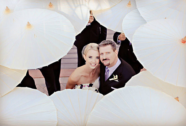 A couple is holding each other in front of some white balloons.