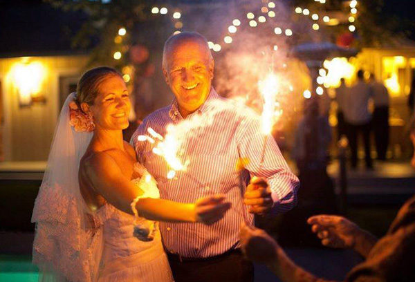 A man and woman holding sparklers in front of lights.