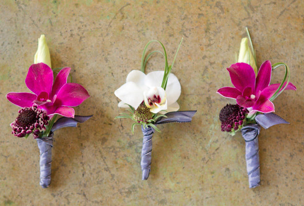 Three boutonnieres of different flowers are shown.