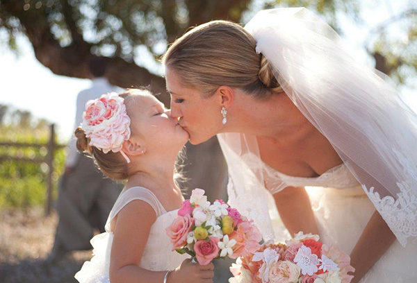 A bride and her daughter kissing each other.