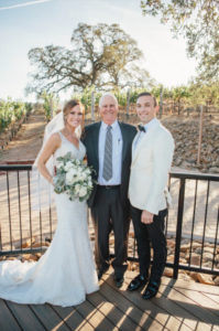 A bride and groom pose with their father.